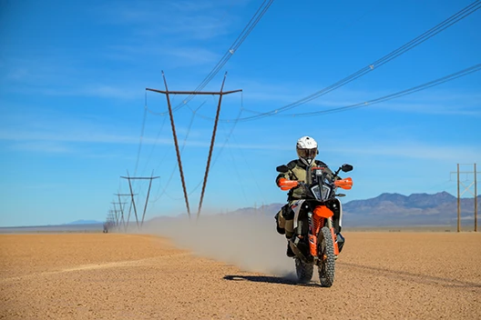 A rider in the Cryomesh gear speeding past a row of powerlines in the wilderness.